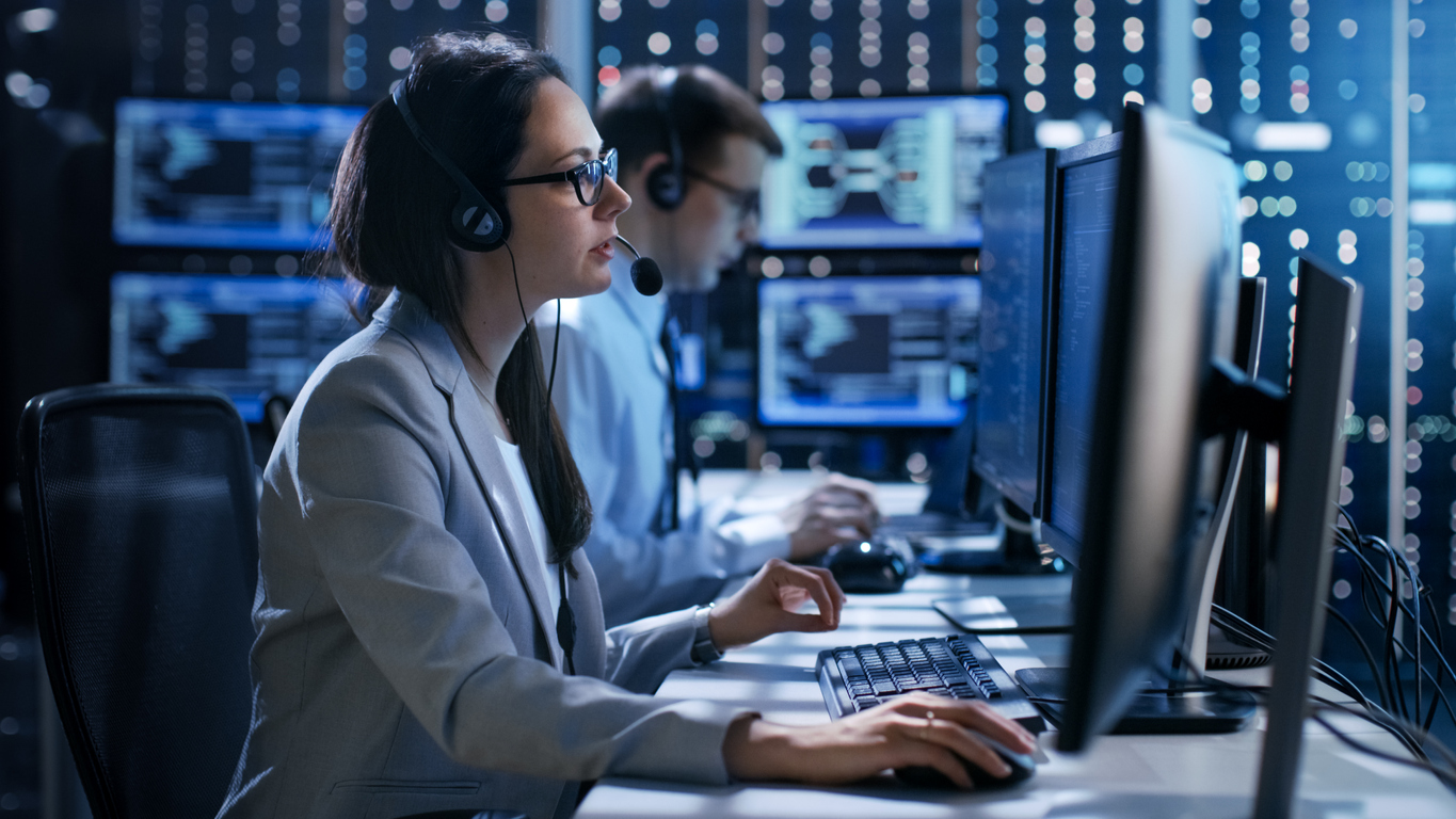 Emergency dispatchers wearing headsets monitoring screens in a 911 response center