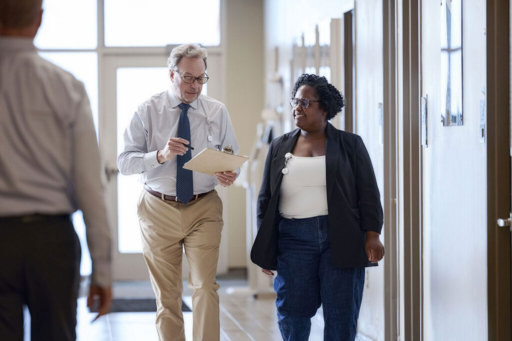 Inspector with a clipboard meeting with a business owner indoors.