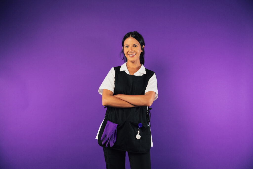 Smiling housekeeper with arms crossed, wearing a ROAR panic button clipped to her apron
