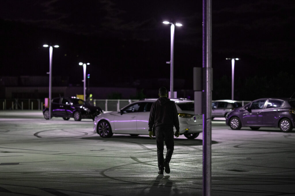 man walking to car in near-empty retail parking lot