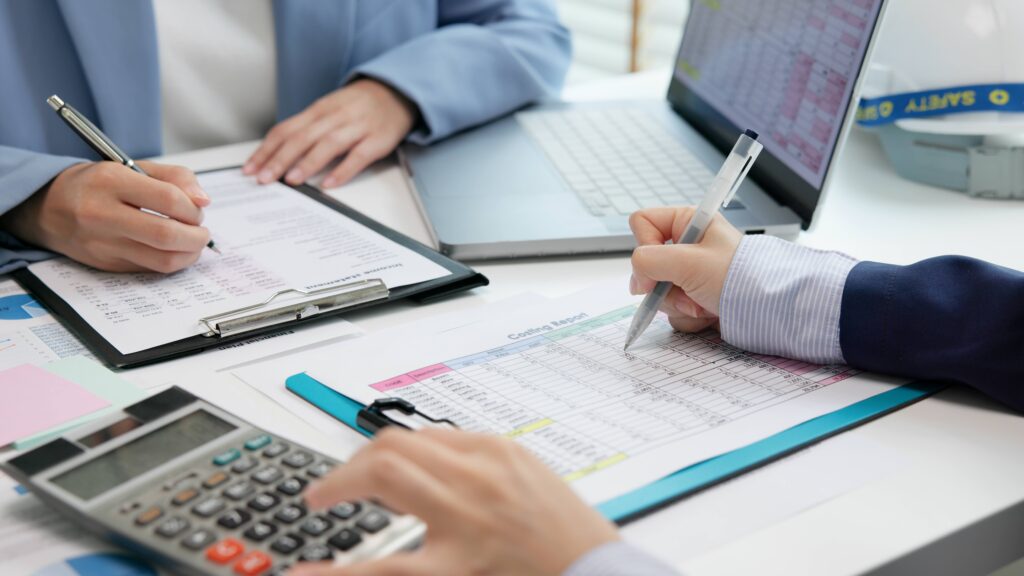 two business workers reviewing financial documents with a calculator